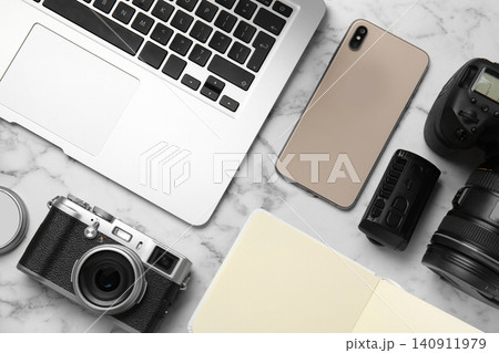 Flat lay composition with laptop, cameras and smartphone on white marble table. Designer's workplace Flat lay composition with laptop, cameras and smartphone on white marble table. Designer's workplace 140911979