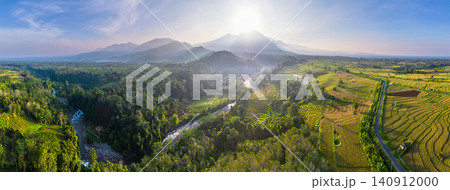 Terraced Rice Fields at Sunrise in Indonesia. Beautiful panoramic view of terraced rice fields surrounded by lush tropical greenery and palm trees Terraced Rice Fields at Sunrise in Indonesia. Beautiful panoramic view of terraced rice fields surrounded by lush tropical greenery and palm trees 140912000