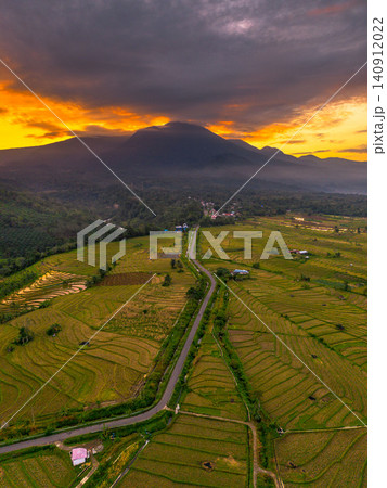 Terraced Rice Fields at Sunrise in Indonesia. Beautiful panoramic view of terraced rice fields surrounded by lush tropical greenery and palm trees Terraced Rice Fields at Sunrise in Indonesia. Beautiful panoramic view of terraced rice fields surrounded by lush tropical greenery and palm trees 140912022