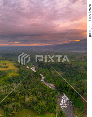 Terraced Rice Fields at Sunrise in Indonesia. Beautiful panoramic view of terraced rice fields surrounded by lush tropical greenery and palm trees 140912026