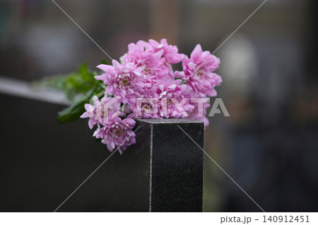 Chrysanthemum flowers on black granite tombstone outdoors. Funeral ceremony Chrysanthemum flowers on black granite tombstone outdoors. Funeral ceremony 140912451