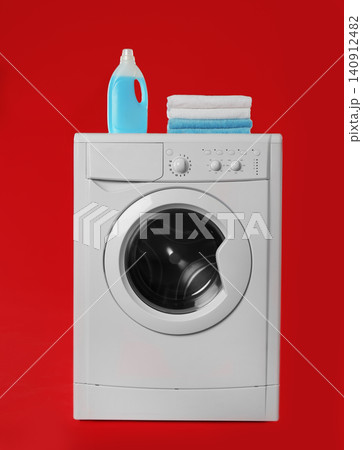Modern washing machine with stack of towels and detergent on red background. Laundry day Modern washing machine with stack of towels and detergent on red background. Laundry day 140912482