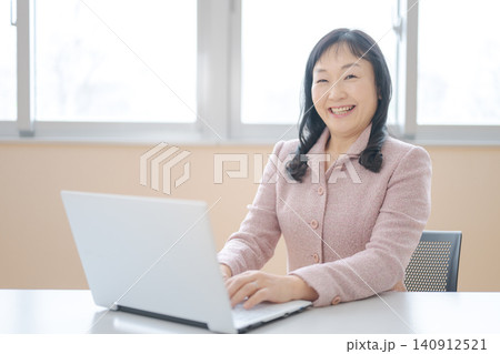 ノートパソコンで作業する笑顔の中年女性 ノートパソコンで作業する笑顔の中年女性 140912521