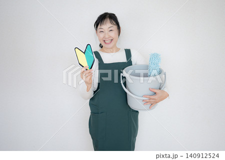 掃除道具と初心者マークを持つ笑顔の女性 掃除道具と初心者マークを持つ笑顔の女性 140912524