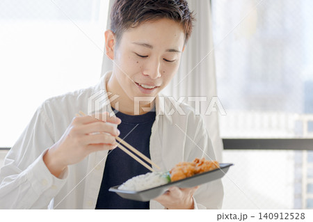 弁当を食べる笑顔の若い男性 弁当を食べる笑顔の若い男性 140912528