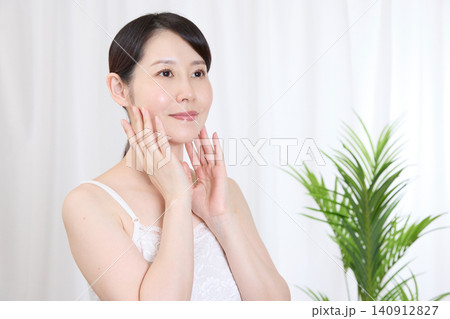 両手で頬を包み込み、肌のうるおいを実感する女性 140912827