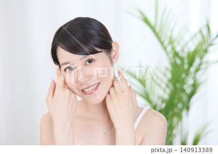 頬に手を添えて美肌をアピールする笑顔の女性 140913389