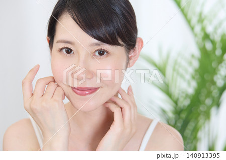 頬に手を添えて美肌をアピールする笑顔の女性 頬に手を添えて美肌をアピールする笑顔の女性 140913395