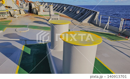 Horizontal close up shot of heavy duty marine mooring bitts with yellow tops on a ship deck, used for securing mooring lines with a deep blue ocean in the background Horizontal close up shot of heavy duty marine mooring bitts with yellow tops on a ship deck, used for securing mooring lines with a deep blue ocean in the background 140913701