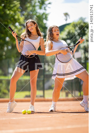 Young women playing air guitar with tennis rackets Young women playing air guitar with tennis rackets 140913741