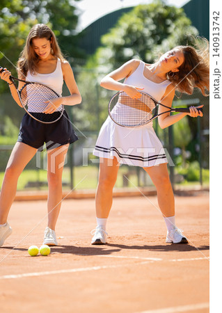 Women having fun playing air guitar with tennis rackets Women having fun playing air guitar with tennis rackets 140913742