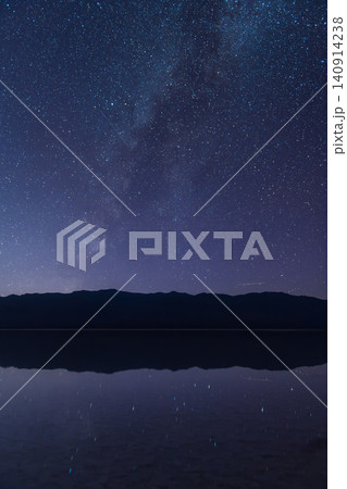 Sierra Nevada mountain silhouette under starry night sky with Milky Way reflection on calm water 140914238