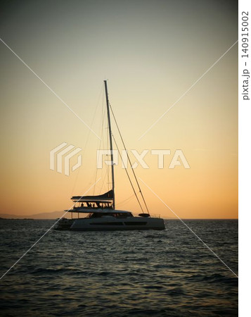 Silhouetted sailboat gliding across calm sea at sunset Silhouetted sailboat gliding across calm sea at sunset 140915002