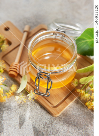Fresh linden honey jar with blooming flowers Fresh linden honey jar with blooming flowers 140915120