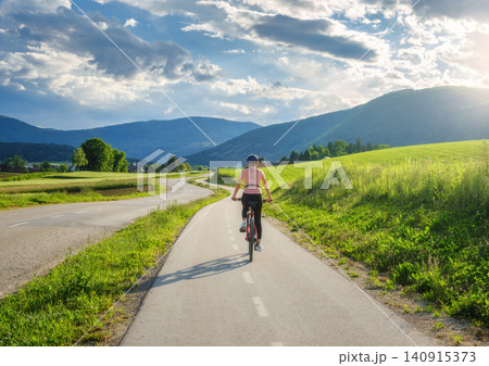Woman riding mountain bike on asphalt bicycle path in countryside 140915373
