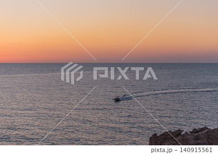A boat serenely sailing on calm waters at sunrise or sunset. 140915561