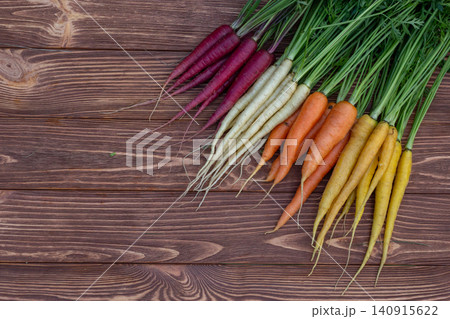 Variety of colorful organic carrots on brown wooden board. Variety of colorful organic carrots on brown wooden board. 140915622