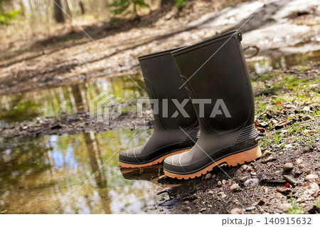 Black gum boots are at the puddle and mud in the yard in spring. Black gum boots are at the puddle and mud in the yard in spring. 140915632