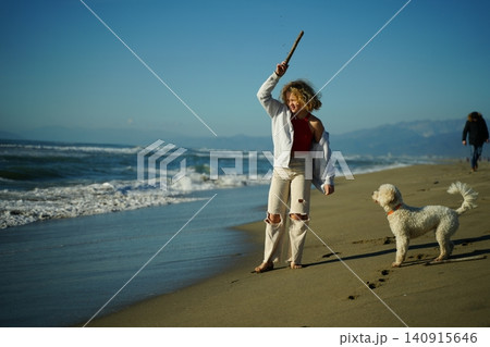 Teen Girl Playing With Dog On Beach 140915646