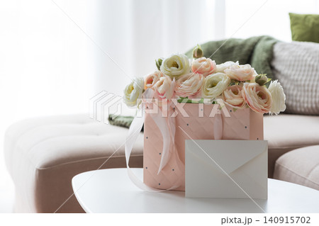Pink gift bag with ranunculus flowers and blank envelope Pink gift bag with ranunculus flowers and blank envelope 140915702