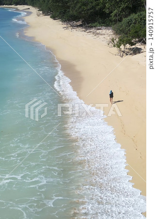 Alone woman wandering barefoot along sunriselit beach with peaceful surroundings Alone woman wandering barefoot along sunriselit beach with peaceful surroundings 140915757