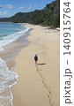Alone woman wandering barefoot along sunriselit beach with peaceful surroundings 140915764