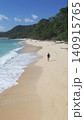 Alone woman wandering barefoot along sunriselit beach with peaceful surroundings 140915765