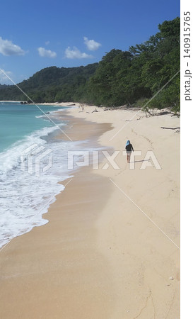 Alone woman wandering barefoot along sunriselit beach with peaceful surroundings Alone woman wandering barefoot along sunriselit beach with peaceful surroundings 140915765