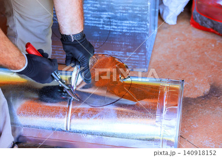 Plumber uses tin snips to cut metal sheet for heating duct work during HVAC assemble Plumber uses tin snips to cut metal sheet for heating duct work during HVAC assemble 140918152