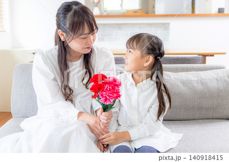 お母さんにカーネーションの花束を渡す女の子 お母さんにカーネーションの花束を渡す女の子 140918415