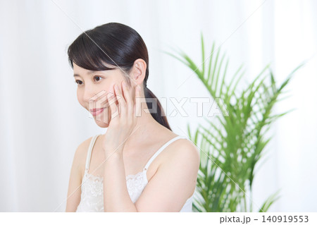 頬に触れながら微笑む美肌の女性 頬に触れながら微笑む美肌の女性 140919553