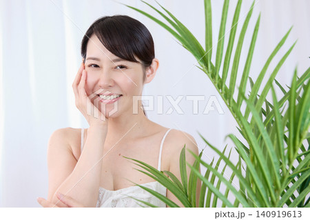 手で頬に触れながら美肌を実感する笑顔の女性 手で頬に触れながら美肌を実感する笑顔の女性 140919613