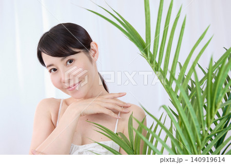 手で頬に触れながら美肌を実感する笑顔の女性 140919614
