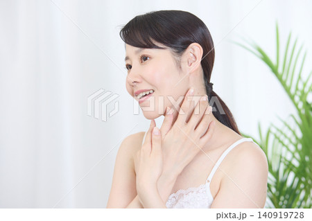 首元に手を添えて笑顔を見せる美肌の日本人女性 首元に手を添えて笑顔を見せる美肌の日本人女性 140919728