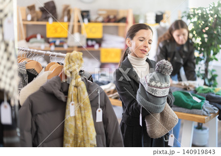 Female shopper chooses a hat in clothing store Female shopper chooses a hat in clothing store 140919843