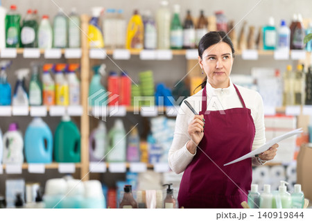 saleswoman writes down on paper the amount of the remaining goods in the warehouse saleswoman writes down on paper the amount of the remaining goods in the warehouse 140919844