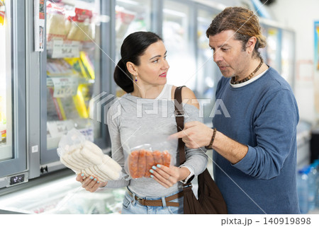Couple in supermarket choose cooled raw sausages Couple in supermarket choose cooled raw sausages 140919898