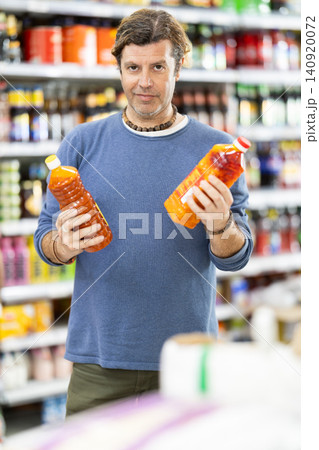Man in supermarket choose drink Man in supermarket choose drink 140920072