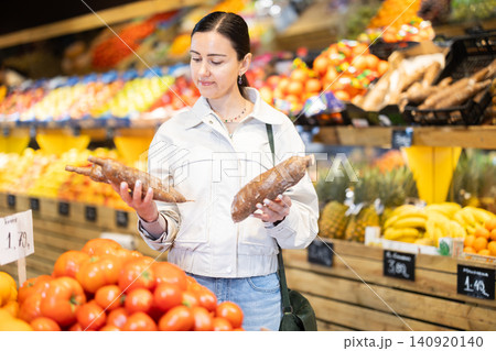 Middle-aged woman choosing cassavas in grocery store Middle-aged woman choosing cassavas in grocery store 140920140
