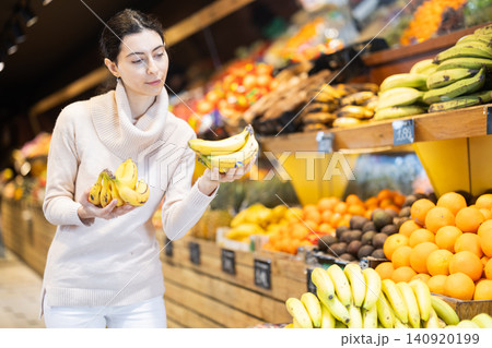Woman choosing bananas in the store Woman choosing bananas in the store 140920199