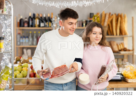 Couple choosing meats and cheese in Christmas decorated store 140920322
