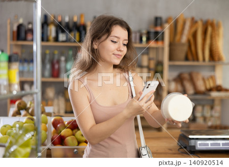 Woman scanning QR code on cheese package for info in grocery Woman scanning QR code on cheese package for info in grocery 140920514