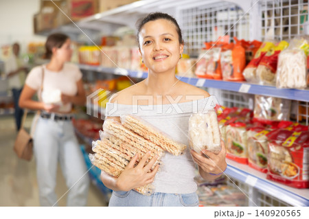 Young Asian woman choosing noodles in grocery section of supermarket Young Asian woman choosing noodles in grocery section of supermarket 140920565