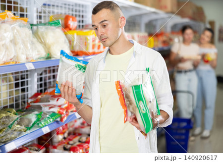 Man comparing different noodle packages in Asian grocery store 140920617