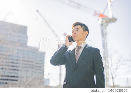 建設現場で電話する若いビジネスマン 建設現場で電話する若いビジネスマン 140920993