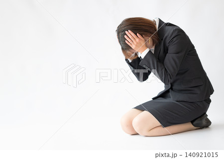 頭を抱えて落ち込む女性会社員 頭を抱えて落ち込む女性会社員 140921015
