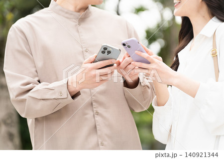 スマートフォンを操作している若い男女 ライフスタイルイメージ スマートフォンを操作している若い男女 ライフスタイルイメージ 140921344