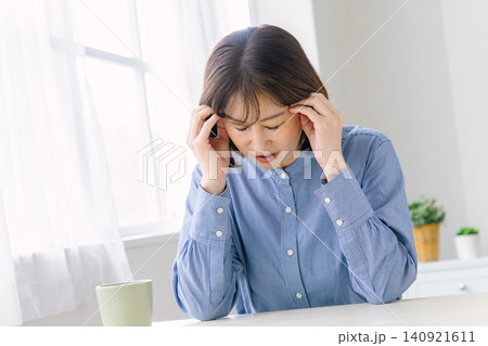 辛そうな表情でこめかみを押さえるミドル女性 辛そうな表情でこめかみを押さえるミドル女性 140921611