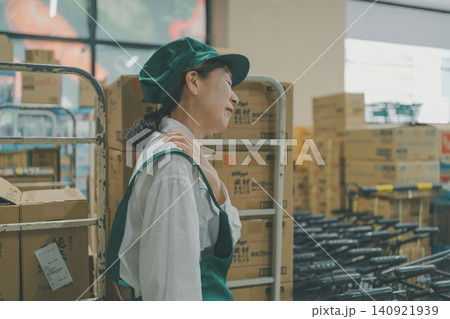 バックヤードで肩の痛みに苦しむ女性スタッフ バックヤードで肩の痛みに苦しむ女性スタッフ 140921939