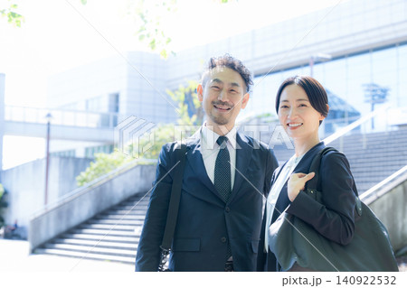 オフィス街で笑顔のカメラ目線のミドルの日本人ビジネスパーソン男女　営業や会社員、共働きの通勤イメージ 140922532